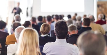 Image of people attending a conference and listening to a presentation